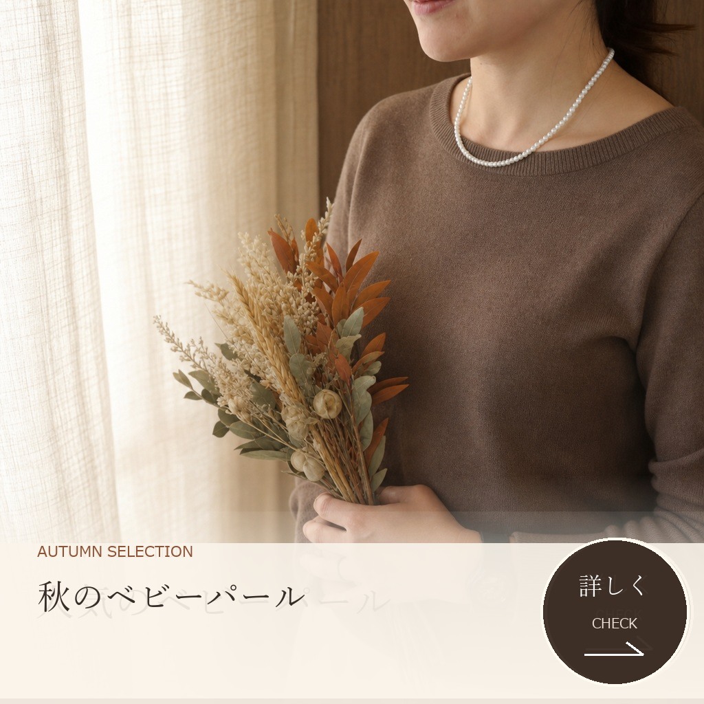 秋色ニットに小粒のベビーパールネックレスを合わせた女性